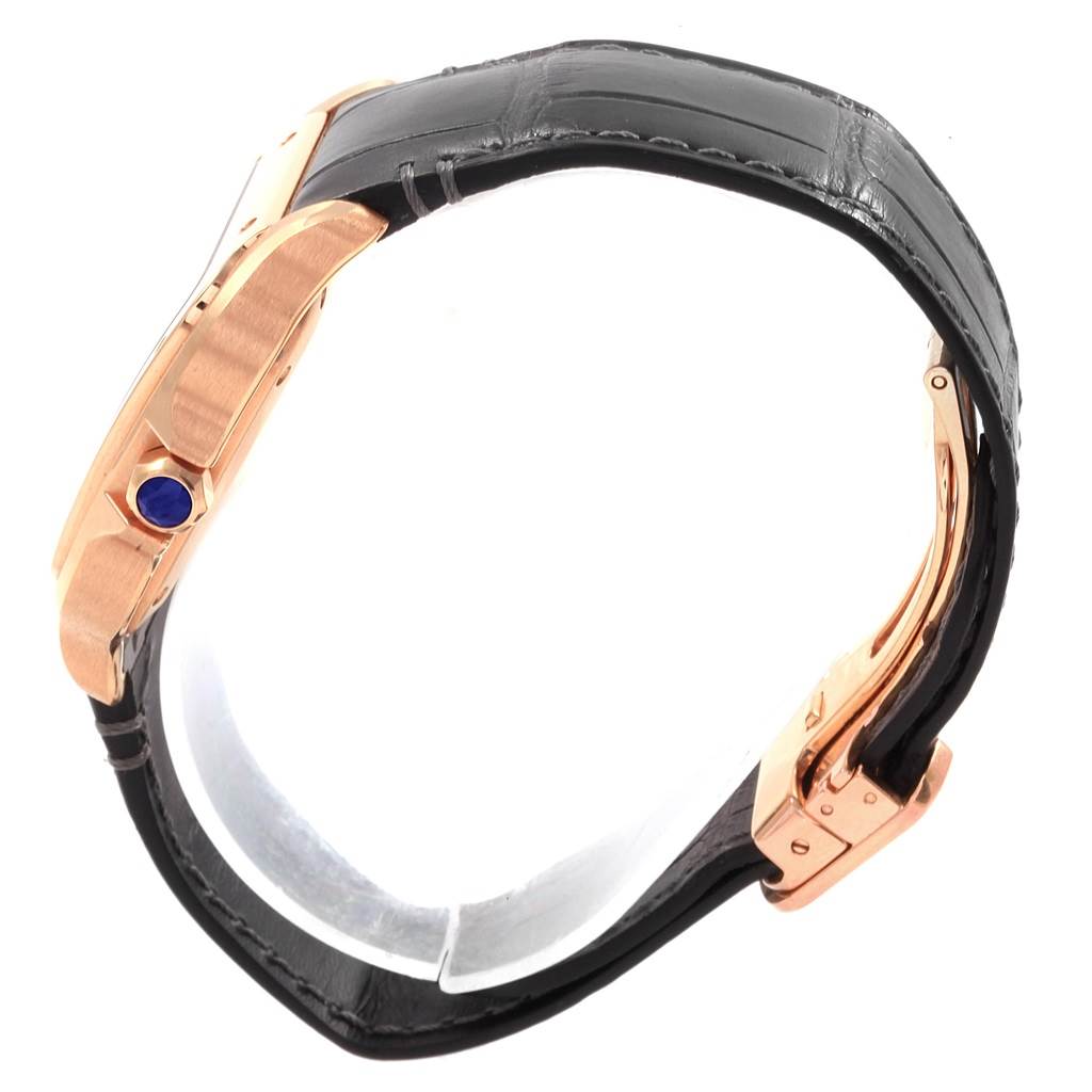 The image shows a side view of a Santos model by Cartier, highlighting its rose gold case, blue cabochon crown, and black leather strap.