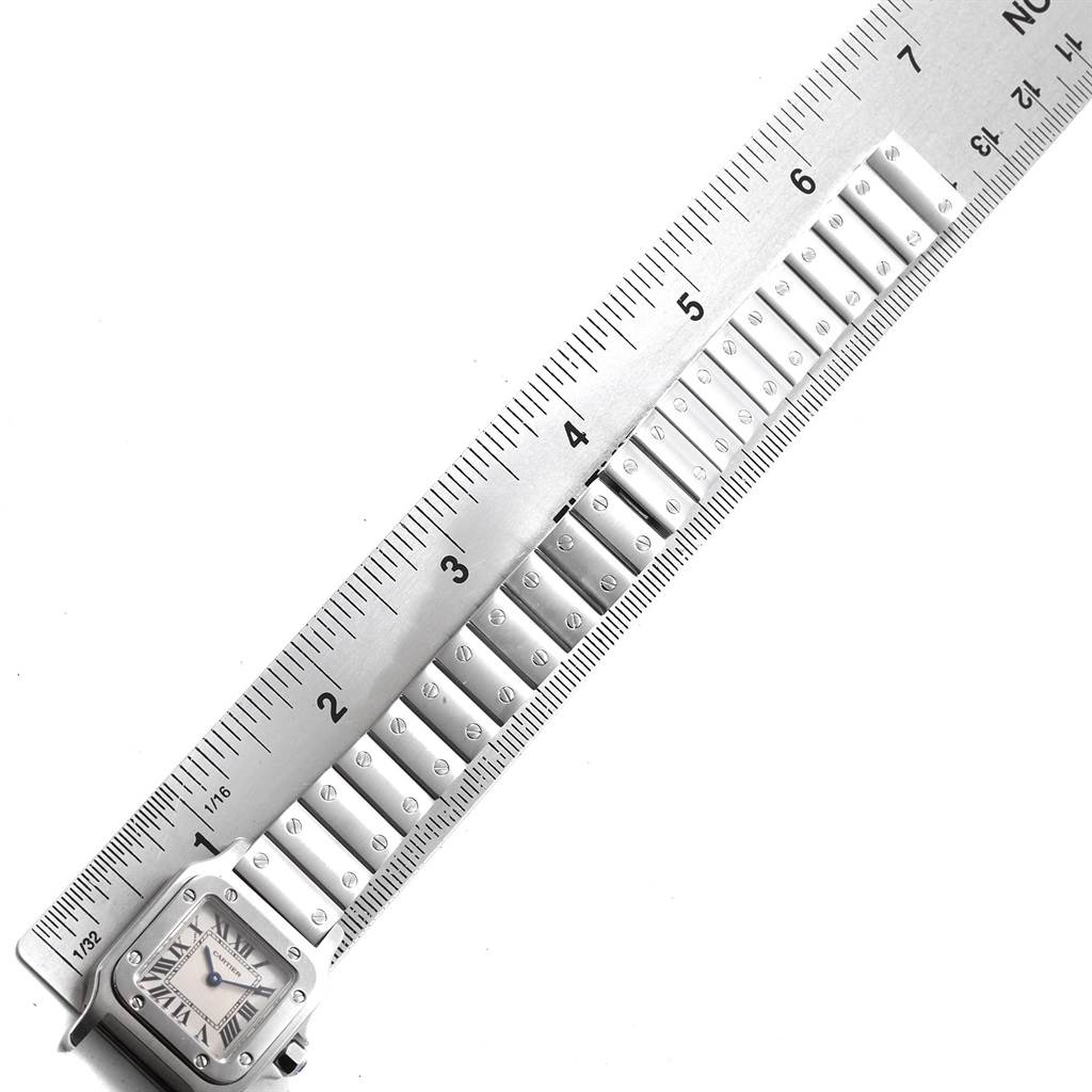The image shows a Cartier Santos W20056D6 Women's Stainless Steel Silver Dial W20056D6 Women's Stainless Steel Silver Dial watch lying along a ruler, highlighting its face and bracelet.