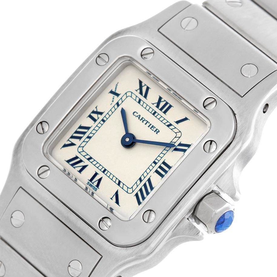The image shows a close-up of the Cartier Santos 1565 Women's Stainless Steel Silver Dial 1565 Women's Stainless Steel Silver Dial watch face, crown, and part of the bracelet.