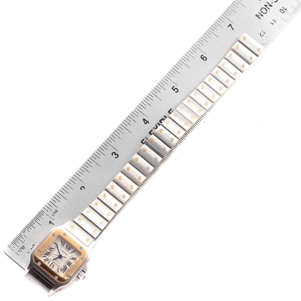 The image shows a top view of a Cartier Santos W20057C4 Women's Stainless Steel Silver Dial W20057C4 Women's Stainless Steel Silver Dial watch, focusing on the face and bracelet laid next to a ruler.