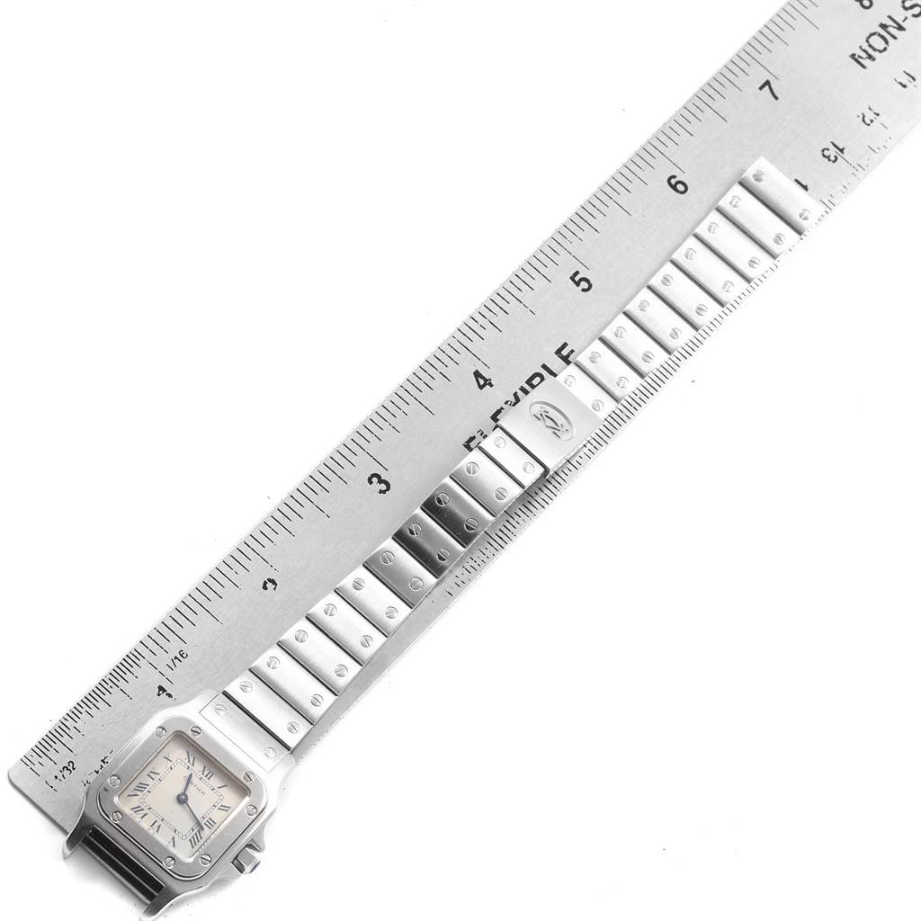 The image shows the full band and face of a Santos model watch by Cartier, next to a ruler for scaling.