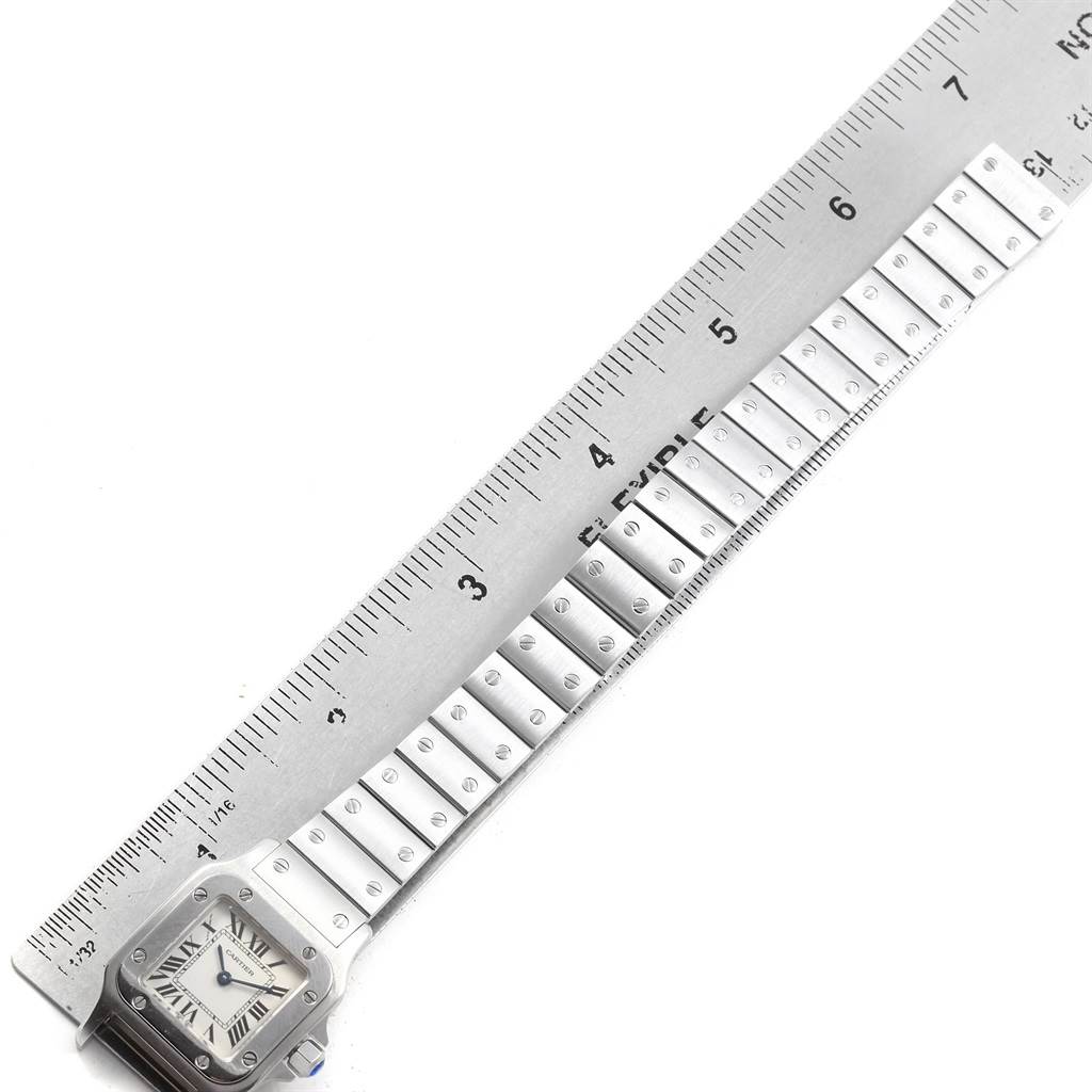 The image shows the Cartier Santos W20056D6 Women's Stainless Steel Silver Dial W20056D6 Women's Stainless Steel Silver Dial watch laid flat next to a ruler, displaying the face and part of the metal bracelet.
