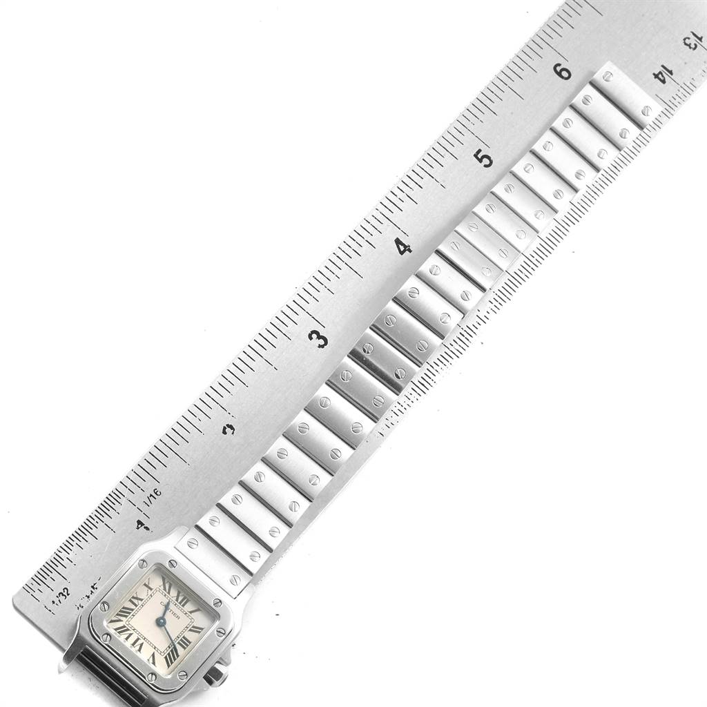 The image shows a vertical view of the Santos model by Cartier, displaying its face and bracelet alongside a ruler for scale.