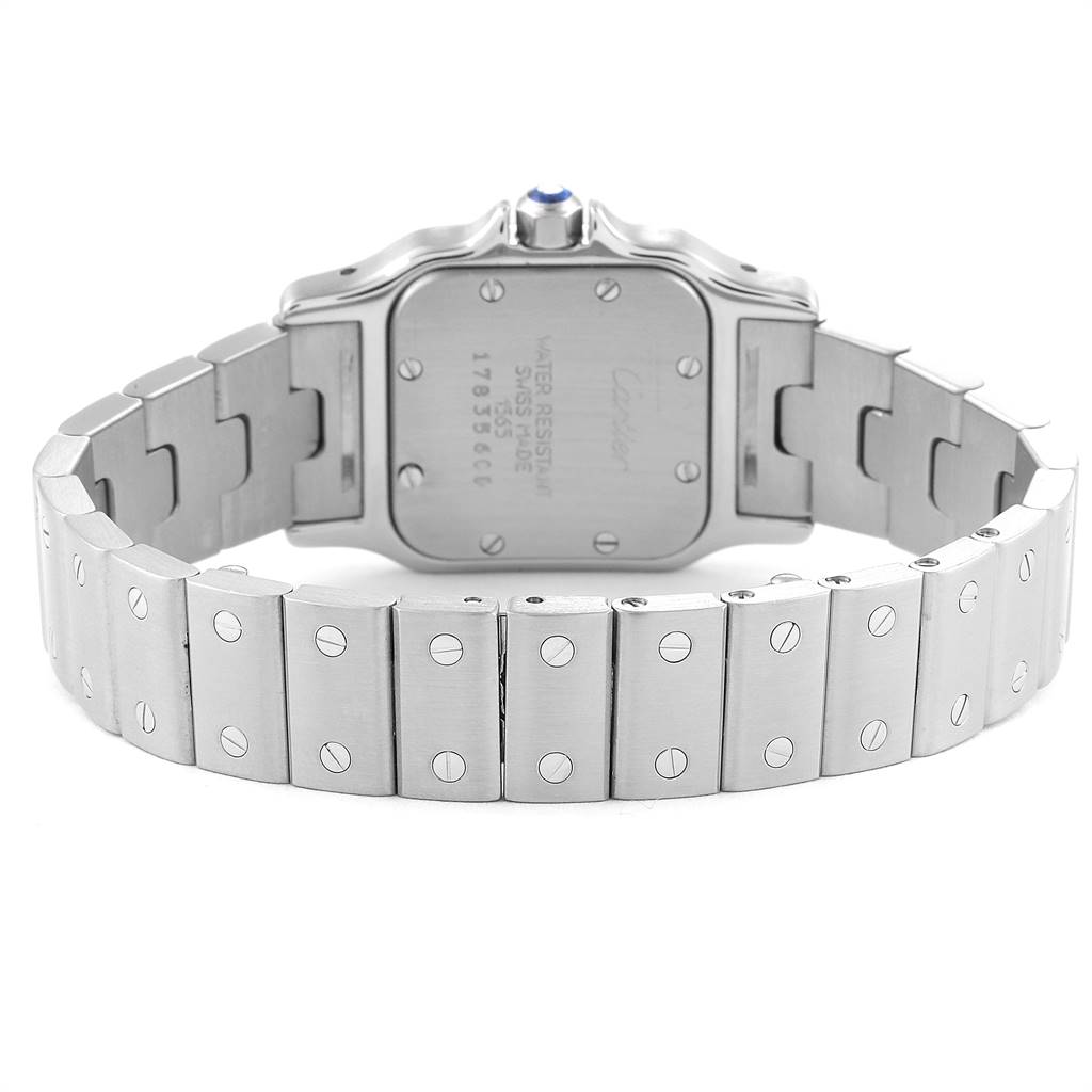 The image shows the back of a Santos model watch by Cartier, including the case back and part of the metallic bracelet.