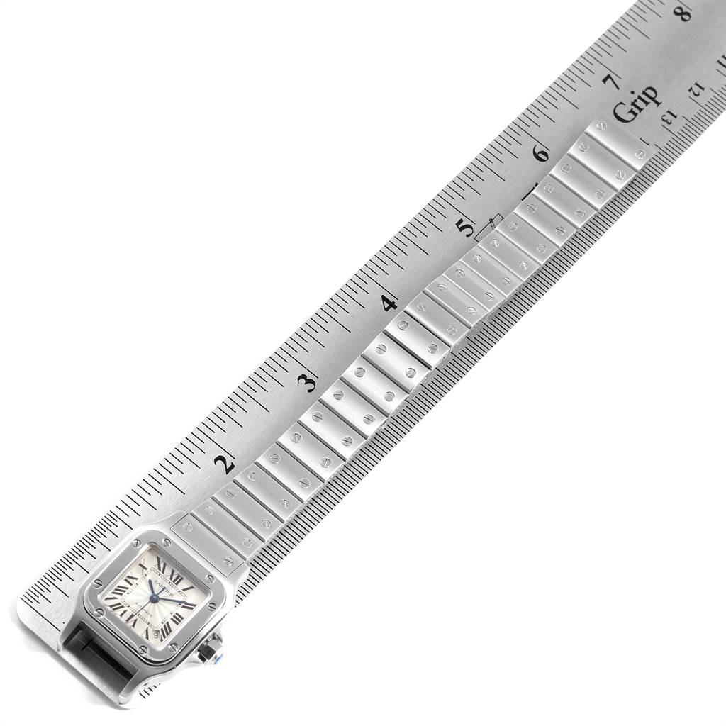 This image shows the Santos model watch by Cartier, displaying the face and band from a top-down angle alongside a ruler.