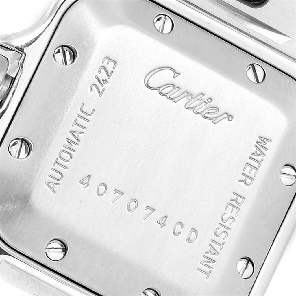 The image shows the back case of a Santos model by Cartier, highlighting its screws and inscriptions.