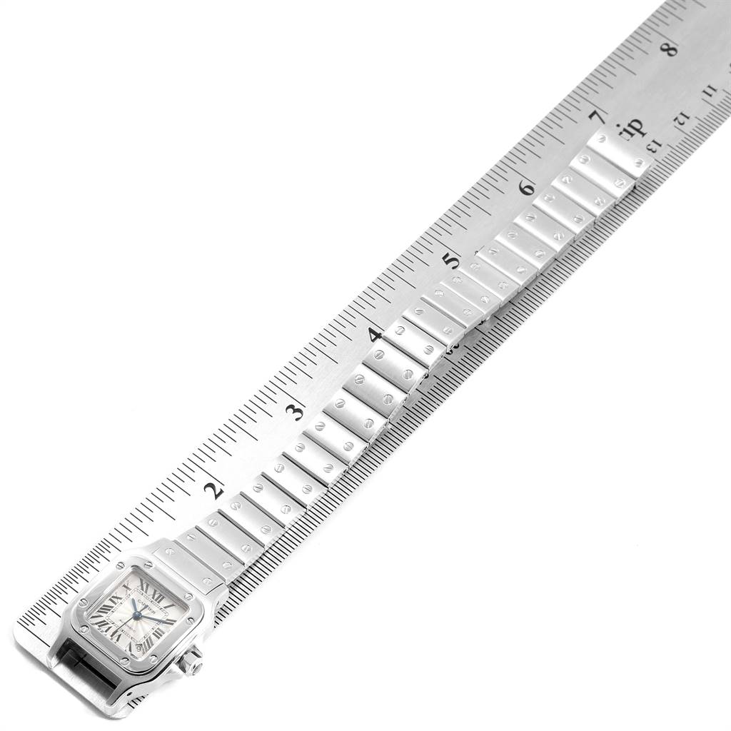 The image shows a Cartier Santos W20044D6 Women's Stainless Steel Silver Dial W20044D6 Women's Stainless Steel Silver Dial watch from a top-down angle, highlighting the face and a portion of its bracelet next to a ruler.