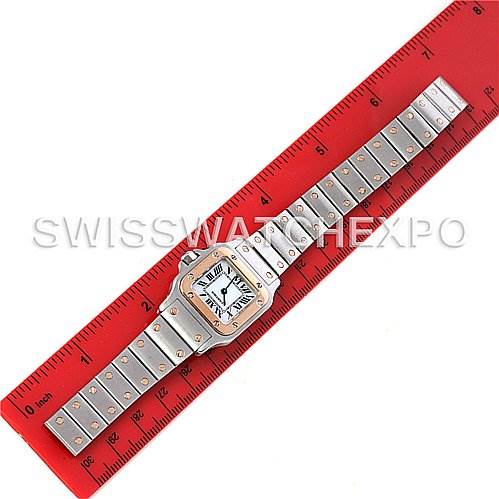 The image shows a Cartier Santos W20012C4 Women's Stainless Steel Mother of Pearl Dial W20012C4 Women's Stainless Steel Mother of Pearl Dial watch laid flat against a red ruler, displaying its face, bezel, and bracelet.