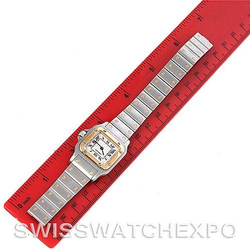 The image shows a Cartier Santos W20012C4 Women
s Stainless Steel Silver Dial W20012C4 Women
s Stainless Steel Silver Dial watch lying flat next to a red ruler for size reference.
