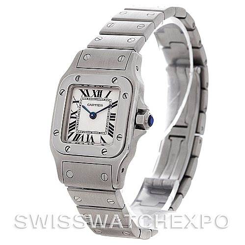 This image shows a Cartier Santos W20056D6 Women
s Stainless Steel Silver Dial W20056D6 Women
s Stainless Steel Silver Dial watch from a three-quarter angle, highlighting its silver case, bracelet, and blue cabochon crown.