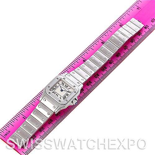 The Cartier Santos W20056D6 Women
s Stainless Steel Silver Dial W20056D6 Women
s Stainless Steel Silver Dial watch is shown flat and fully extended, placed next to a pink ruler for size reference.
