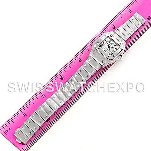 The image shows a Santos model by Cartier laid flat next to a pink ruler, displaying both the face and the entire bracelet.