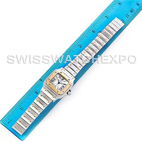 The image shows a Santos model by Cartier, displayed flat with a ruler for measurement, highlighting the watch face and bracelet.