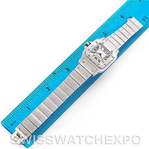 The image shows a Cartier Santos W20056D6 Women
s Stainless Steel Silver Dial W20056D6 Women
s Stainless Steel Silver Dial model watch laid out flat with its face and metal bracelet visible, placed adjacent to a blue ruler for measurement.