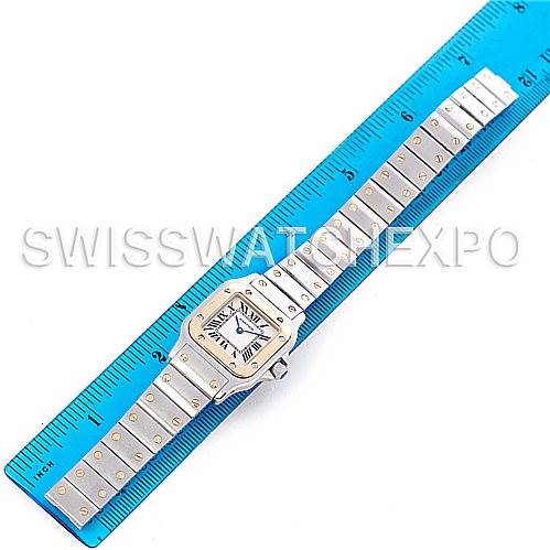 The image shows a top-down view of the Cartier Santos W20012C4 Women
s Stainless Steel Silver Dial W20012C4 Women
s Stainless Steel Silver Dial watch, with its face and full metal bracelet laid alongside a blue ruler.