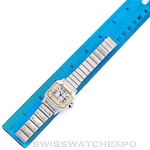 The image shows an overhead view of a Santos model watch by Cartier, lying next to a blue ruler for scale.