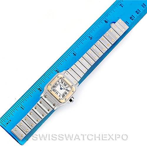 The image shows a Cartier Santos W20012C4 Women's Stainless Steel Silver Dial W20012C4 Women's Stainless Steel Silver Dial watch laid flat alongside a blue ruler, displaying the watch face and metal band.