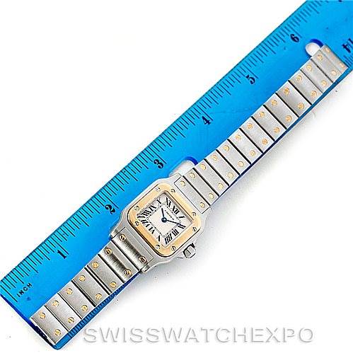 The image shows a Cartier Santos W20012C4 Women's Stainless Steel Silver Dial W20012C4 Women's Stainless Steel Silver Dial watch laid flat next to a blue ruler, displaying the watch's face and bracelet.