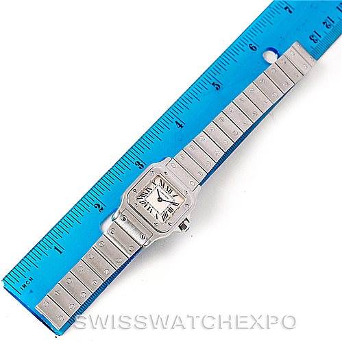 The Cartier Santos W20056D6 Women
s Stainless Steel Silver Dial W20056D6 Women
s Stainless Steel Silver Dial watch is shown from a top-down angle alongside a ruler, displaying its square dial and metal bracelet.