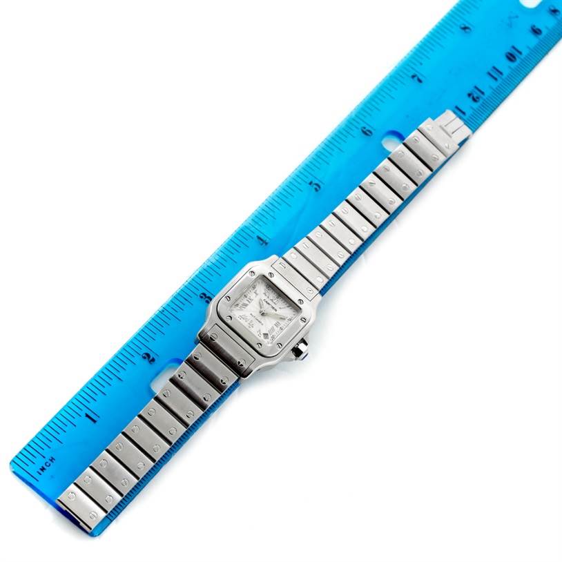 The image shows a Cartier Santos W20044D6 Women
s Stainless Steel Silver Dial W20044D6 Women
s Stainless Steel Silver Dial watch laid flat next to a blue ruler for measurement.