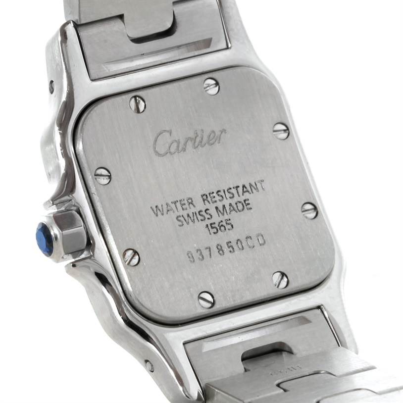 The image shows the back case and part of the bracelet of a Santos model by Cartier at an angle highlighting its inscription and screws.