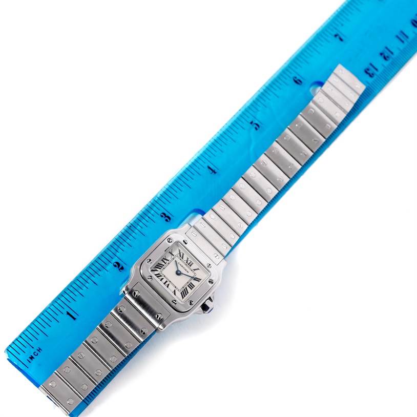 The Cartier Santos W20056D6 Women
s Stainless Steel Silver Dial W20056D6 Women
s Stainless Steel Silver Dial watch is shown from a top-down angle alongside a ruler for scale.