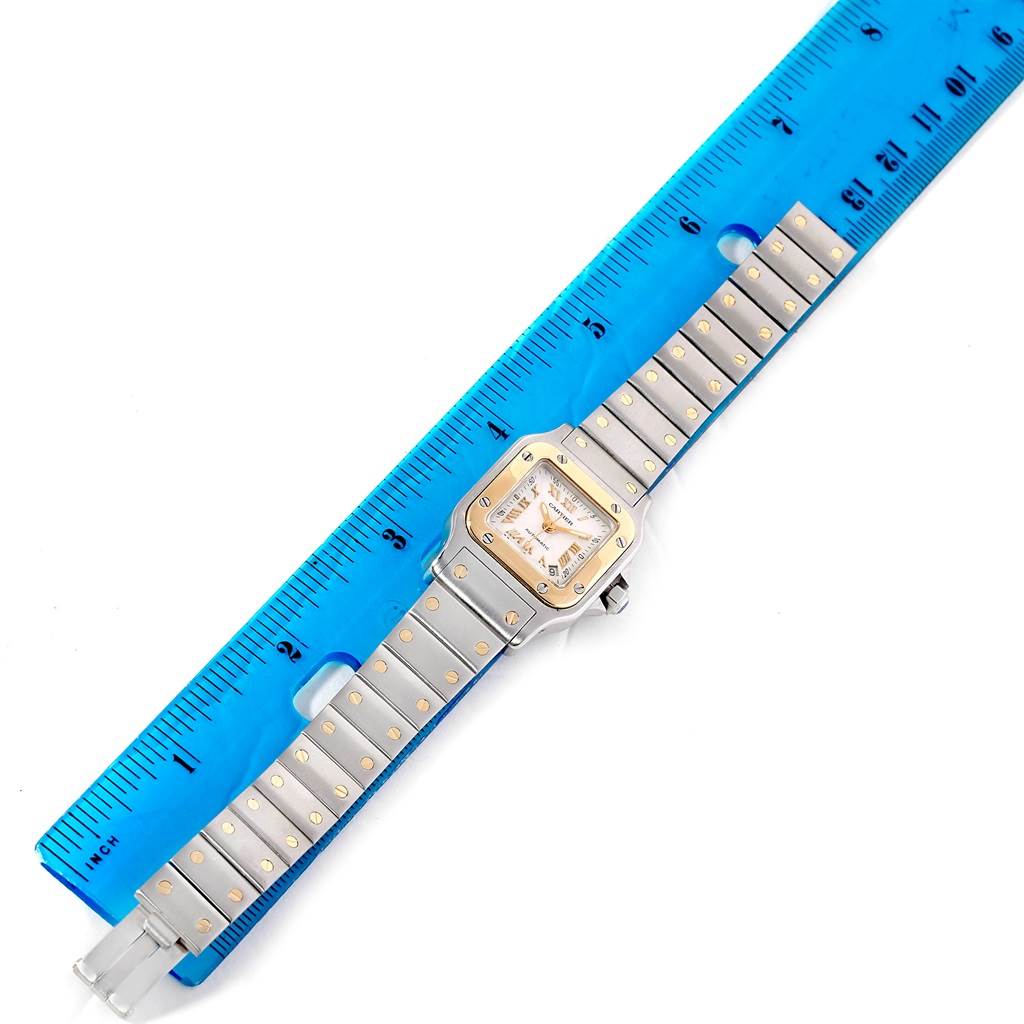 The Santos model by Cartier is shown from a top-down angle, with both the case and bracelet displayed next to a ruler for size reference.