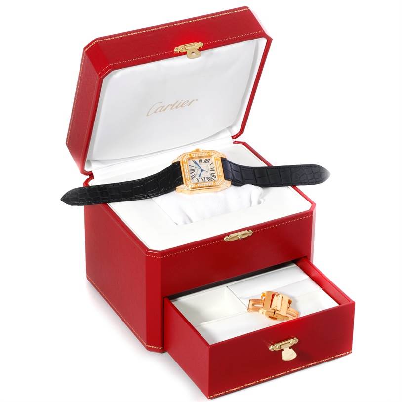 This image shows a Cartier Santos WM502051 Yellow Gold Silver Dial WM502051 Yellow Gold Silver Dial model watch displayed in an open red case, with an additional bracelet accessory stored in a drawer.