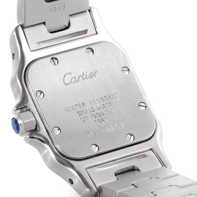 The image shows the back case of a Cartier Santos W20012C4 Women
s Stainless Steel Silver Dial W20012C4 Women
s Stainless Steel Silver Dial watch, including the inscriptions and part of the bracelet and crown with a blue cabochon.