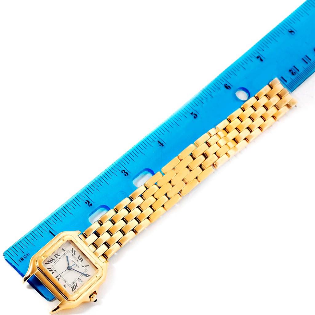 The image shows a Cartier Panthere W25014B9 Men's Yellow Gold Silver Dial W25014B9 Men's Yellow Gold Silver Dial watch lying flat next to a blue ruler with its face and part of the bracelet visible.