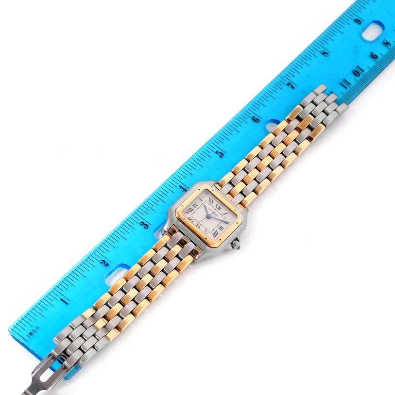 The image shows a Cartier Panthère watch laid flat beside a blue ruler, highlighting its length and two-tone bracelet design.