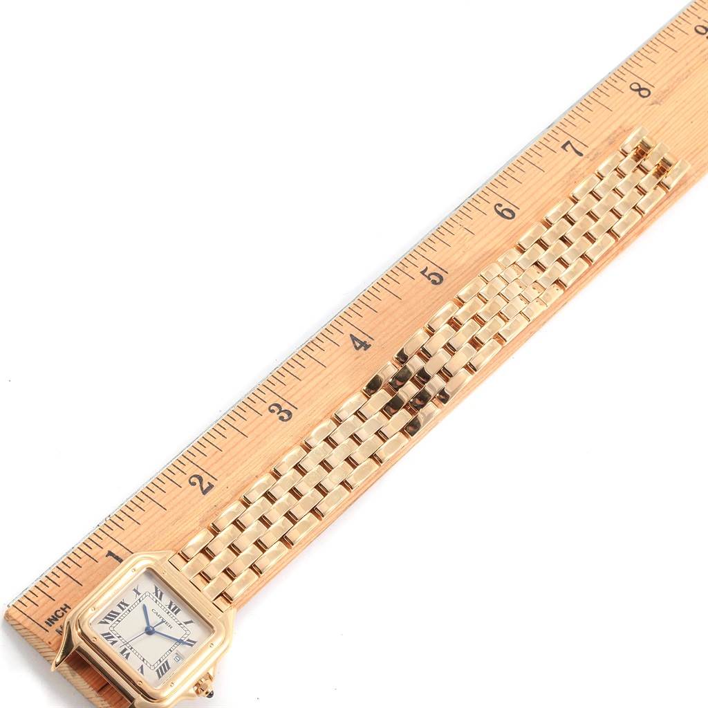 The image shows a Cartier Panthere W25014B9 Men's Yellow Gold Silver Dial W25014B9 Men's Yellow Gold Silver Dial watch laid flat next to a ruler, highlighting the face and bracelet of the watch.