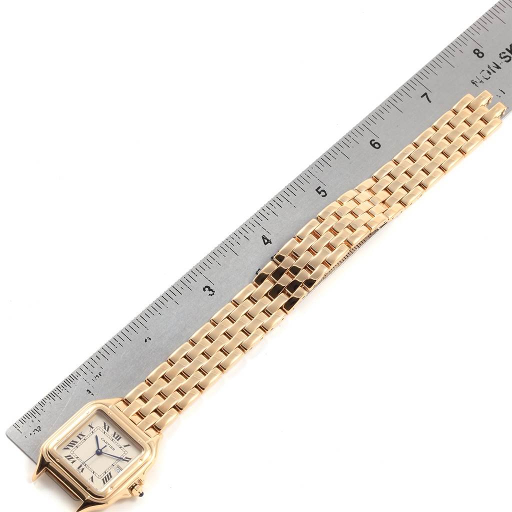 The image shows the front of a Cartier Panthere W25014B9 Men's Yellow Gold Silver Dial W25014B9 Men's Yellow Gold Silver Dial watch with the band extended alongside a ruler, displaying its length and detailing.