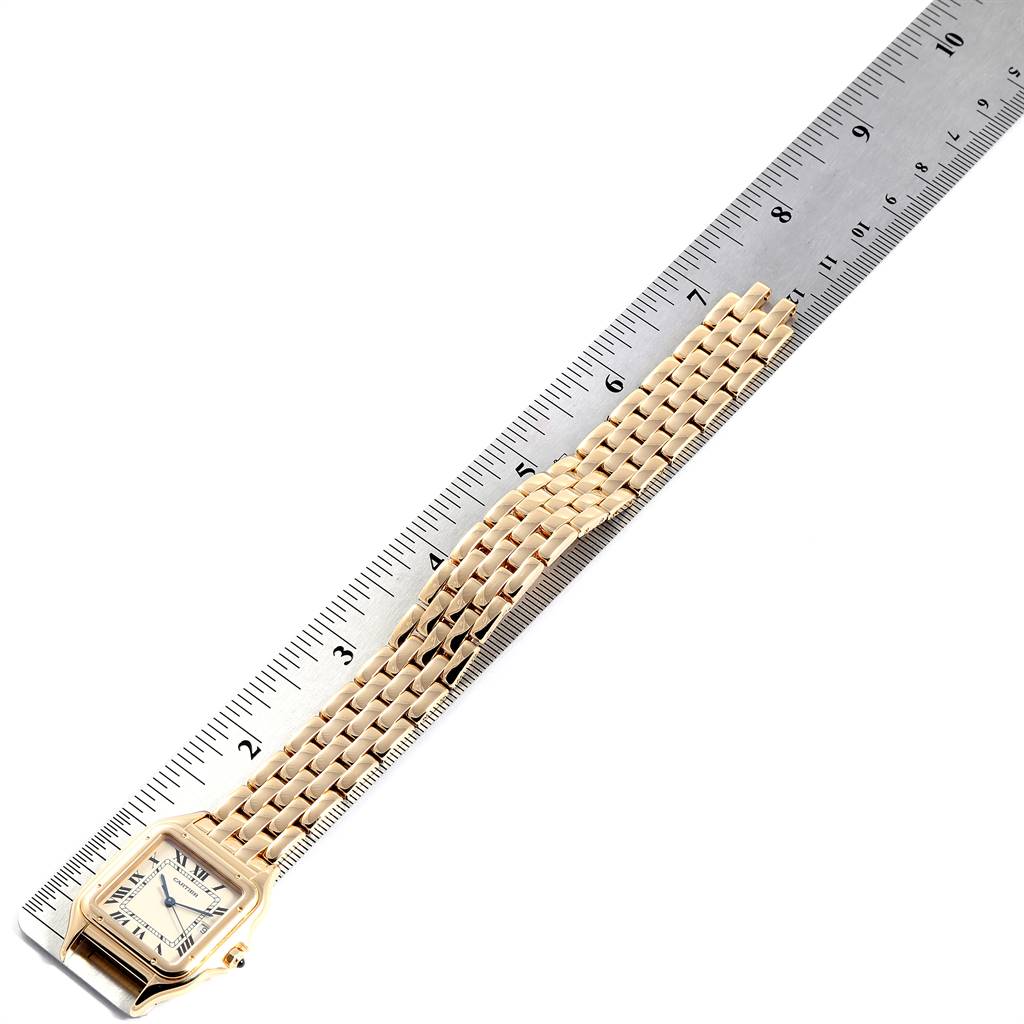 The image shows a Panthere model by Cartier watch laid flat alongside a metal ruler, displaying its face and bracelet band.