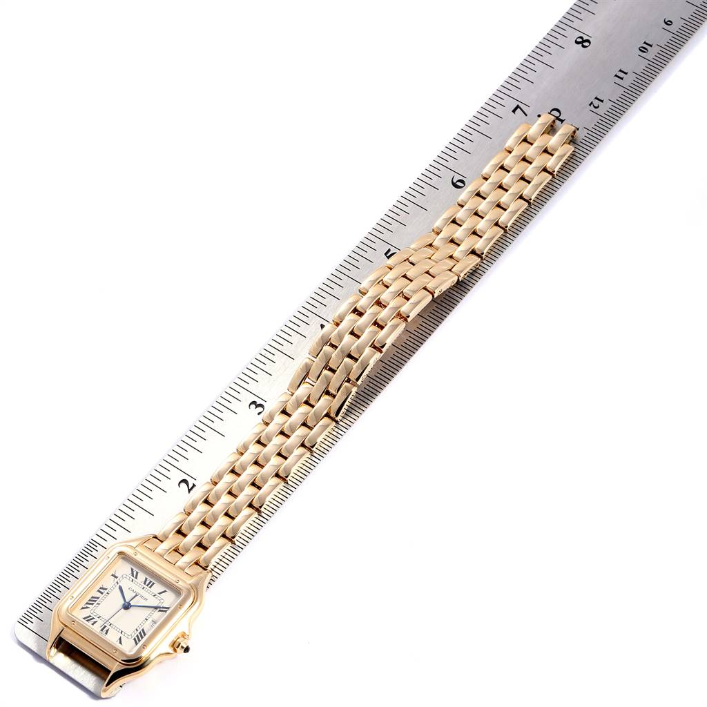 The image shows a Cartier Panthère watch lying flat against a ruler, highlighting the face and chain bracelet.