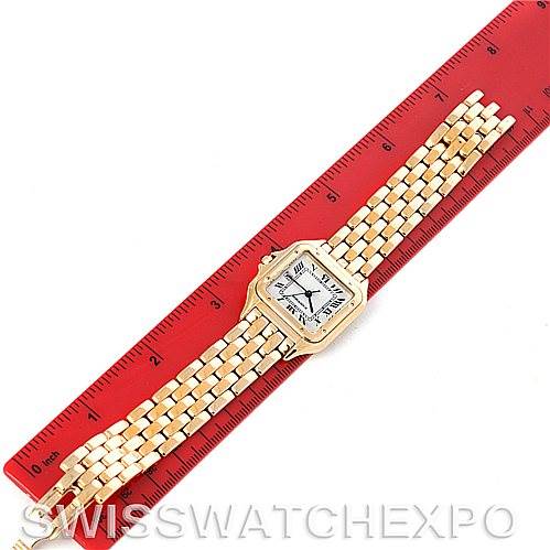 This image shows a Panthere model watch by Cartier laid flat against a red ruler, showcasing the face and bracelet in full length.