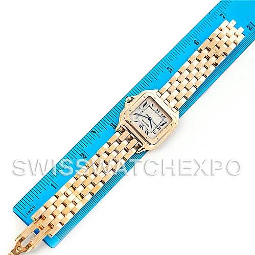 The image shows a top-down view of a Cartier Panthere W25014B9 Men
s Yellow Gold Silver Dial W25014B9 Men
s Yellow Gold Silver Dial watch, set against a blue ruler, highlighting its detailed gold bracelet and square face.