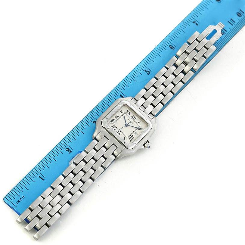 The image shows a top-down view of a Cartier Panthere W25032P5 Men's Stainless Steel Silver Dial W25032P5 Men's Stainless Steel Silver Dial watch with a metal bracelet next to a blue ruler.