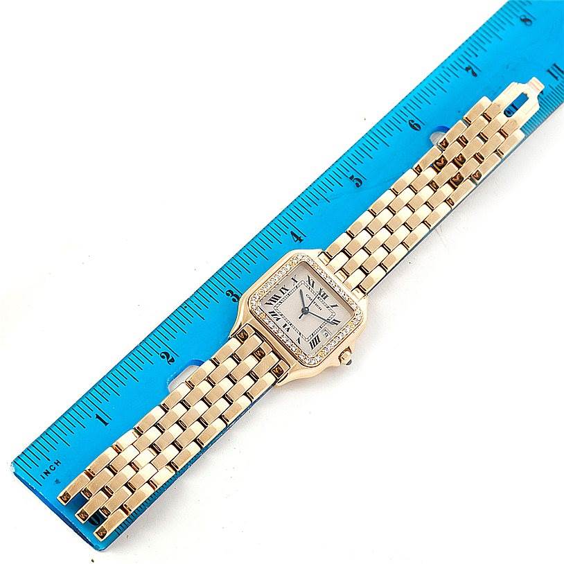 The image shows a Panthere model by Cartier watch laid flat next to a blue ruler, focusing on the face and bracelet.