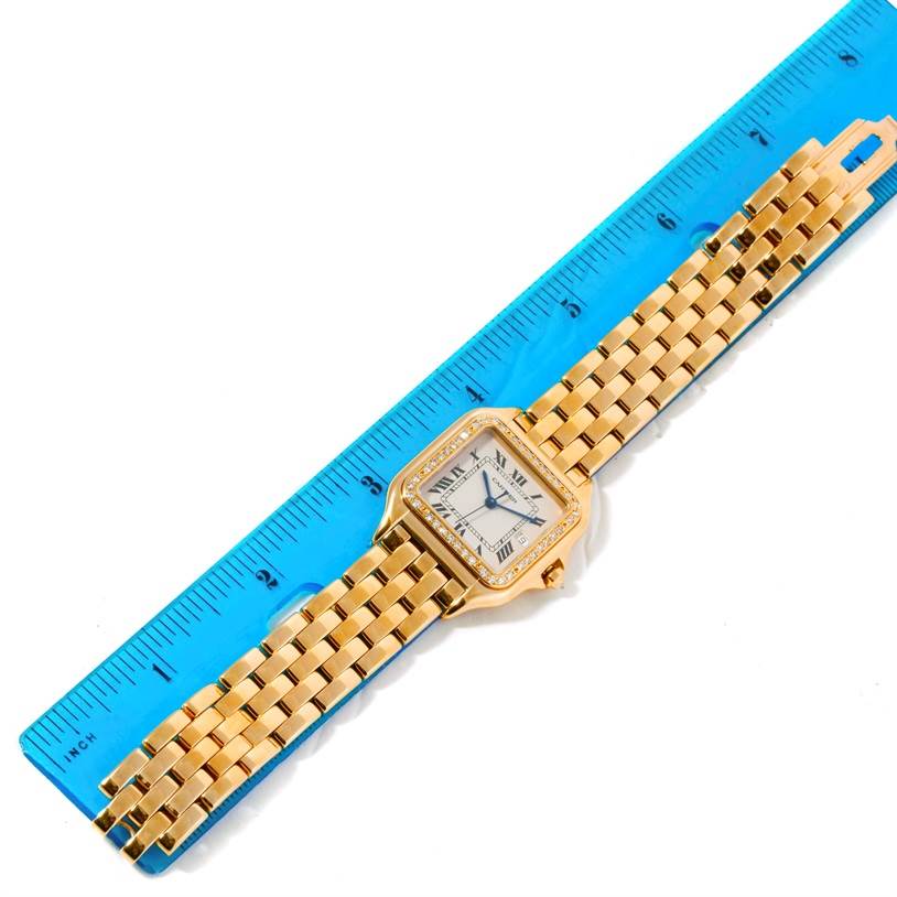 The image shows a Cartier Panthere Men's Yellow Gold Silver Dial Men's Yellow Gold Silver Dial watch laying flat alongside a blue ruler.