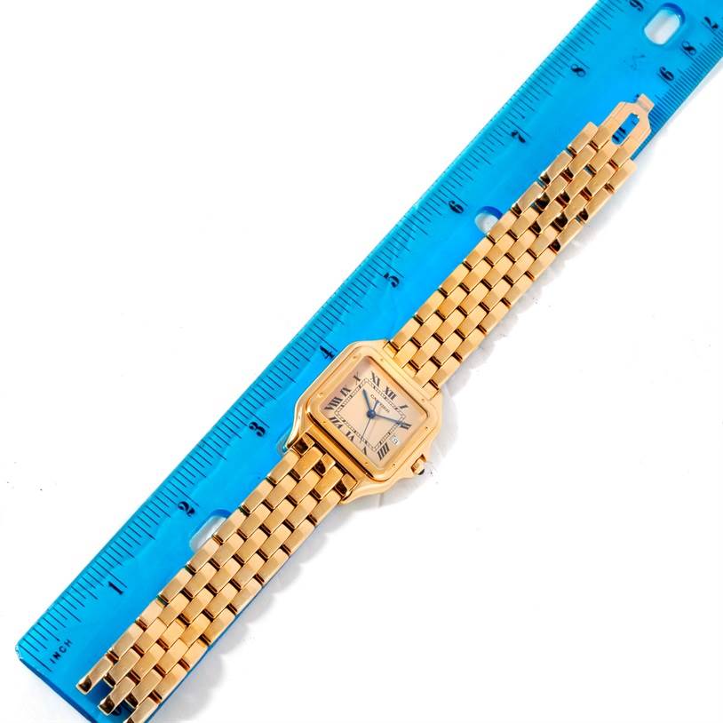 The Cartier Panthere W25014B9 Men's Yellow Gold Beige Dial W25014B9 Men's Yellow Gold Beige Dial watch is shown laid flat with its face and bracelet visible, positioned alongside a blue ruler for scale.