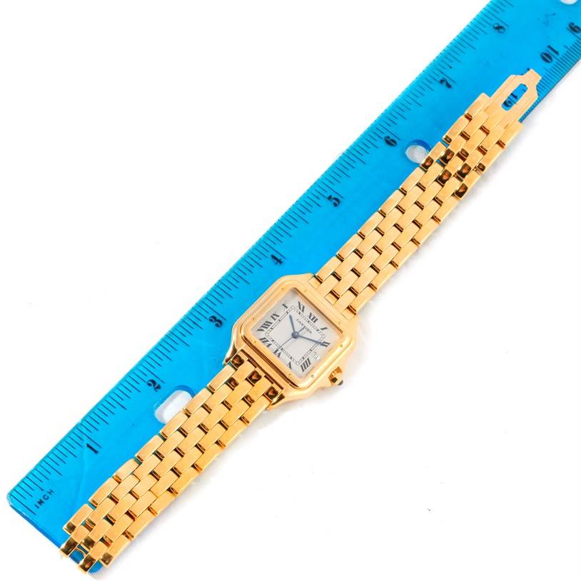 The image shows an overhead view of a Cartier Panthere W25014B9 Men's Yellow Gold Silver Dial W25014B9 Men's Yellow Gold Silver Dial watch, featuring its gold band and square face, placed next to a ruler.