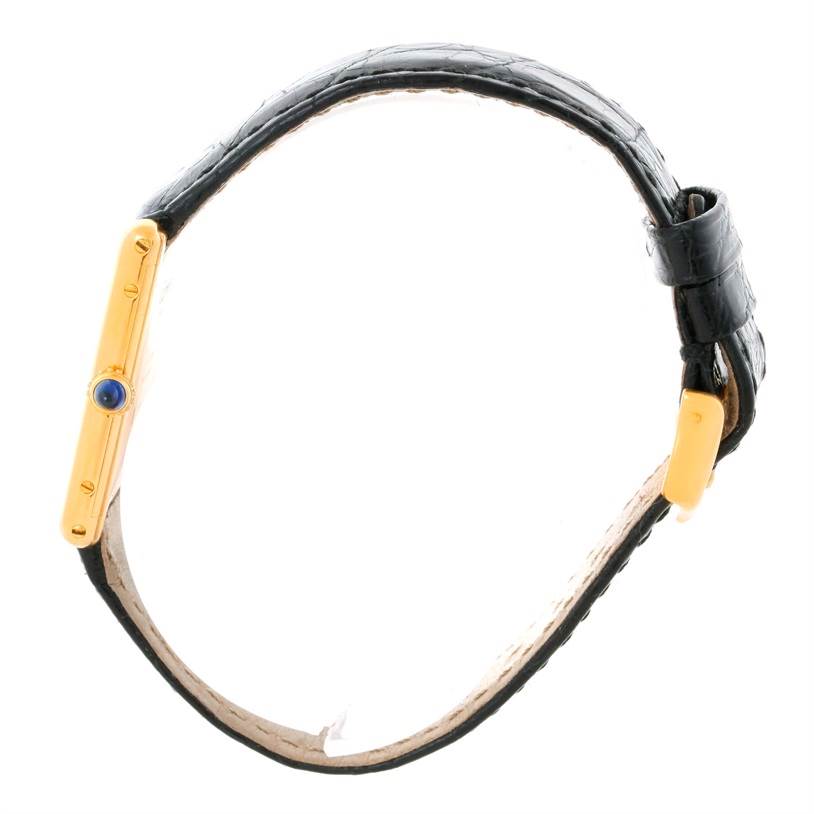 This image shows a side view of the Cartier Tank Classic Men's Yellow Gold Silver Dial Men's Yellow Gold Silver Dial watch, focusing on the gold case, blue crown, and black leather strap.