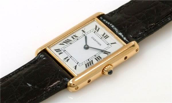 The Cartier Tank Classic Men
s Steel and Gold (two tone) White Dial Men
s Steel and Gold (two tone) White Dial watch is shown from an oblique angle, displaying the face, crown, and part of the black leather strap.