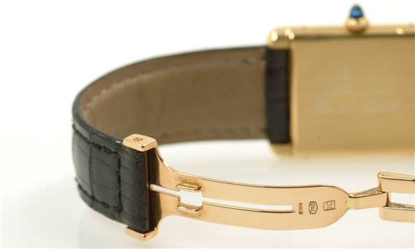 The image shows a close-up of the clasp mechanism and part of the strap of a Cartier Tank Classic Yellow Gold White Dial Yellow Gold White Dial watch.