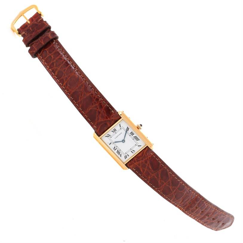 The image shows a top-down view of a Cartier Tank Classic Men
s Yellow Gold White Dial Men
s Yellow Gold White Dial watch with a brown leather strap and gold rectangular case.