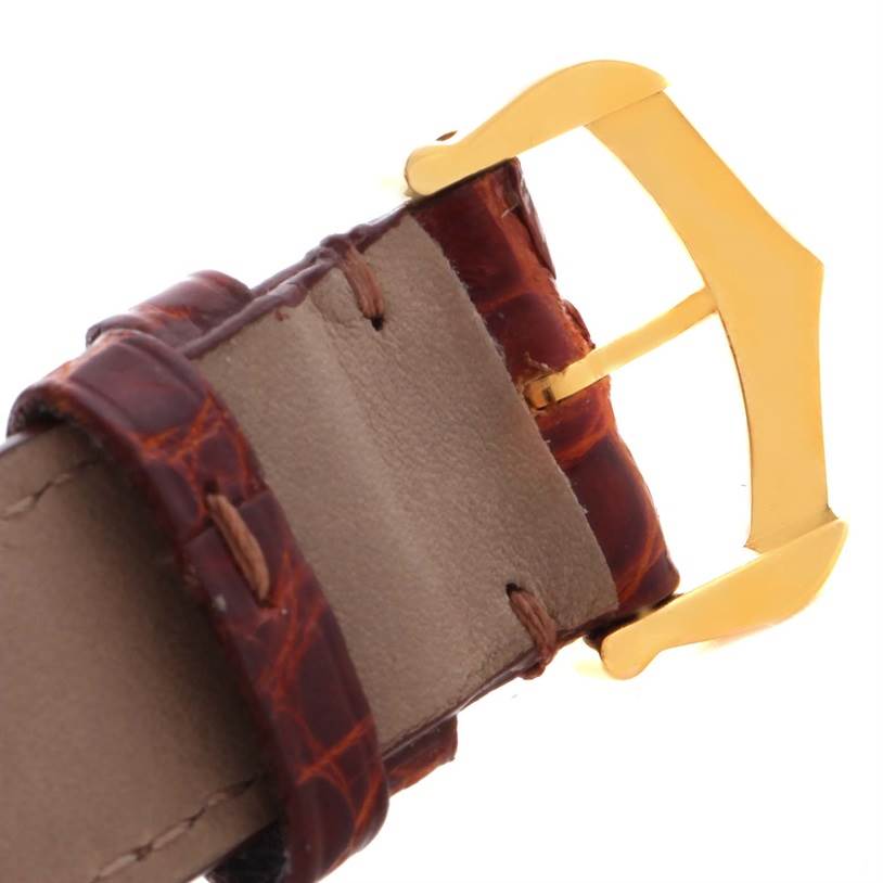 This image shows a close-up of the leather strap and gold buckle of a Cartier Tank Classic Men
s Yellow Gold White Dial Men
s Yellow Gold White Dial watch.