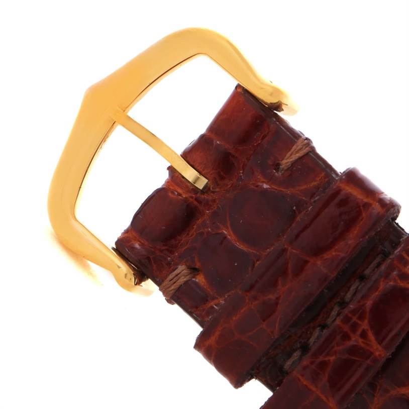 The image shows a close-up of the leather strap and gold buckle of a Cartier Tank Classic Men
s Yellow Gold White Dial Men
s Yellow Gold White Dial watch.