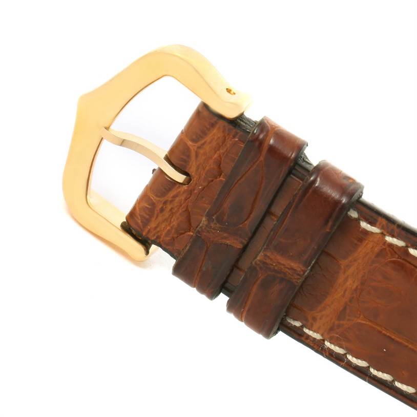 This image shows a close-up of the brown leather strap and gold buckle of a Cartier Tank Classic Yellow Gold White Dial Yellow Gold White Dial watch.