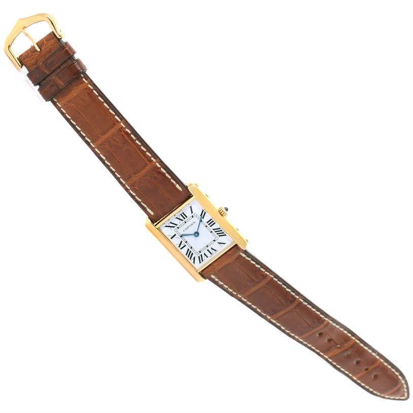 This image shows a Cartier Tank Classic Yellow Gold White Dial Yellow Gold White Dial watch from a top-down angle, displaying its face, brown leather strap, and gold casing.